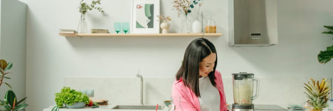 A woman blends fresh ingredients for a healthy smoothie in a stylish kitchen, promoting wellness.